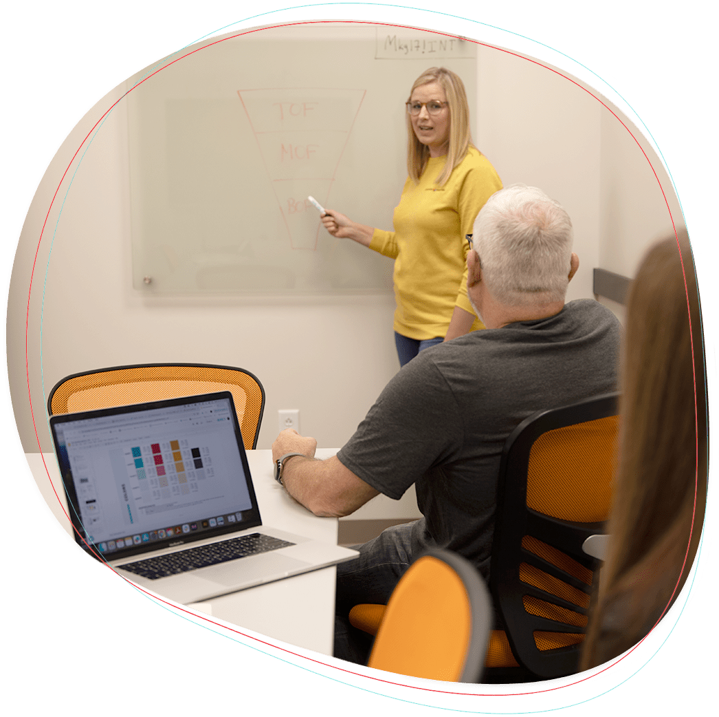 A woman at a white board and man at computer