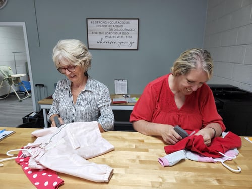 Women tagging baby clothes