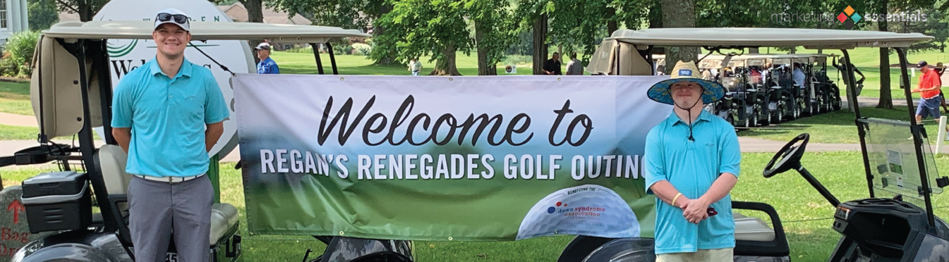 Matt and Alex standing next to Regan’s Renegades Golf Outing banner.